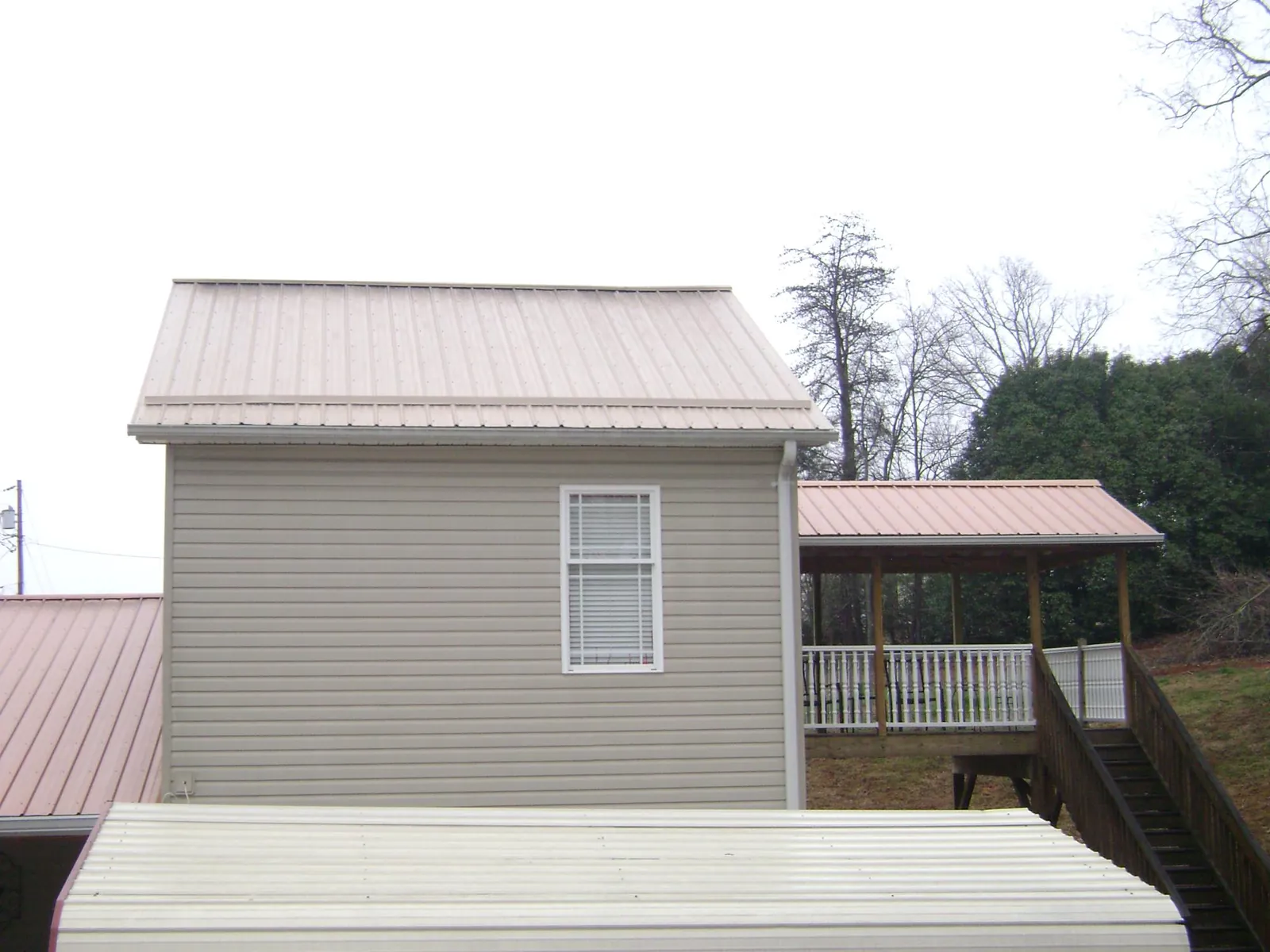 Tan metal roofs on a two story addition and attached porch, from a Roof Replacement job in Downingtown