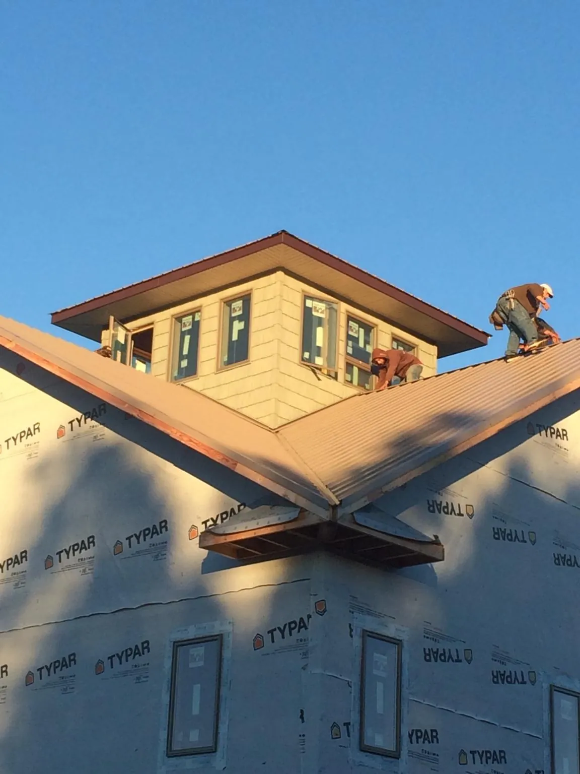 Roofers working around a rooftop cupola on a new metal roof at sunset — Roof Waterproofing in Downingtown by Roofing Brothers
